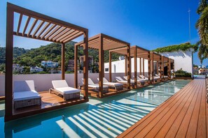 Un espace piscine aménagé sur le toit, avec des chaises longues et des pergolas en bois.