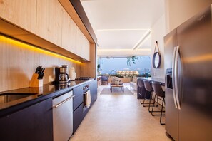 A modern kitchen with a built-in oven, a coffee machine, and a refrigerator.