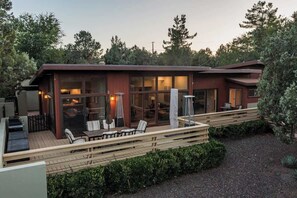 Ein modernes Haus mit Terrasse, Sitzgelegenheit im Freien und einem Feuerkorb.