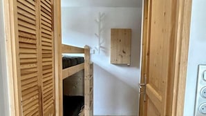 Un pasillo estrecho con paredes de madera y una cama litera.