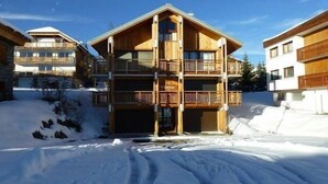 Un edificio de madera de varios pisos con balcones, rodeado de nieve.