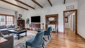 A spacious living room with a wooden ceiling, a sofa, a coffee table, and a TV.