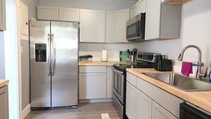 A compact kitchen with a stainless steel refrigerator, microwave, and oven. - Cozy home, close to dining, entertaining, military bases, beaches and more. (North Charleston)