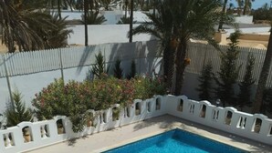 Una piscina rettangolare con bordo piastrellato in bianco, circondata da un recinto bianco con decorazioni intagliate.