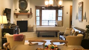 Una sala de estar acogedora con chimenea, asientos cómodos y un amplio ventanal con vistas al exterior.