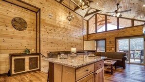 A spacious wooden cabin with a large kitchen island, wooden cabinets, and a dining area with a bench. - Ern806 - Splashin' Views 2 Bedroom Cabin by RedAwning (Sevierville)