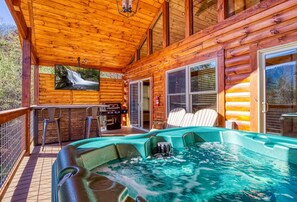 A wooden cabin with a hot tub, outdoor seating, and a waterfall view. - Ern806 - Splashin' Views 2 Bedroom Cabin by RedAwning (Sevierville)