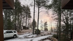 A covered outdoor area with a view of a snowy forest and a parked car.