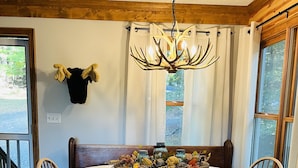 A dining area with a wooden table, chairs, a chandelier, and a decorative centerpiece.