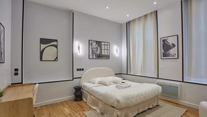 A modern bedroom with a bed, bedside table, and artwork on the walls. - Spacious Air-conditioned Apartment Center of Paris (Paris)