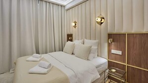 A hotel room with a large bed, beige curtains, and a wooden panel wall.