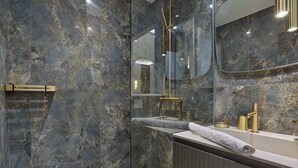 A modern bathroom with marble walls, a glass shower enclosure, and a vanity with a towel.