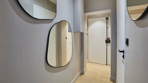 A hallway with three round mirrors on the wall, a door at the end, and a light fixture. - Superb & New Studio Eiffel Tower (Paris)