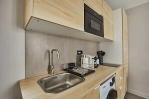 A compact kitchen with a stainless steel sink, a built-in oven, and a dishwasher.