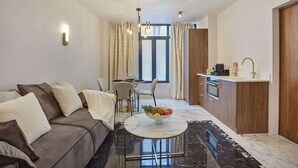 A modern living room with a sofa, a dining table with chairs, a kitchen area with a sink and cabinets, and a large window with curtains. - Magnificent New Apartment Louvre Palais Royal (Paris)