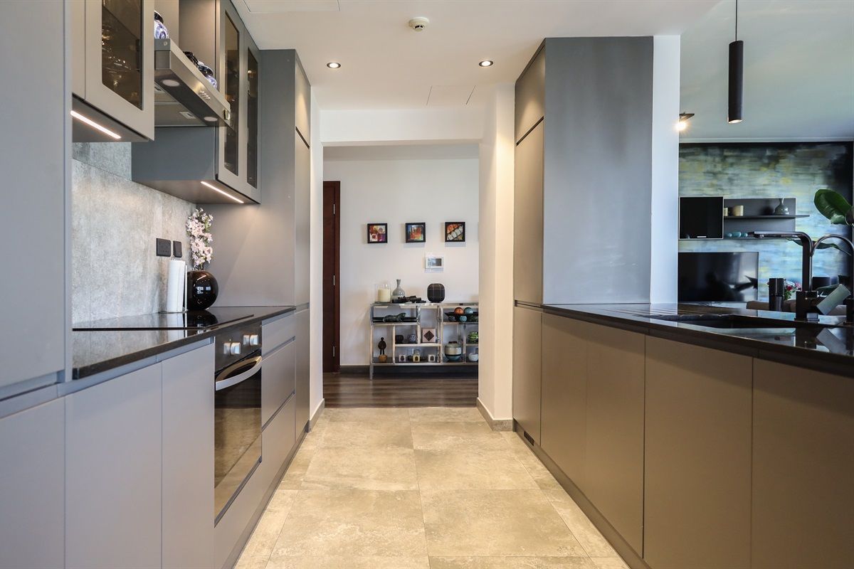 Une cuisine moderne dotée d’appareils électroménagers intégrés, d’un îlot central et donnant sur la salle à manger.