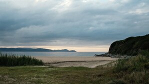 Un paisaje costero con playa, zonas verdes y un acantilado.