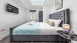 A modern bedroom with a large bed, a TV mounted on the wall, and a skylight above. - Impeccable Ensuite Room in Finsbury Park Londonn19 (London)