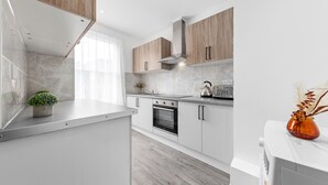 A modern kitchen with white cabinets, a built-in oven, and a stainless steel range hood. - Impeccable Ensuite Room in Finsbury Park Londonn19 (London)