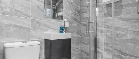 A modern bathroom with a toilet, sink, and glass-enclosed shower.