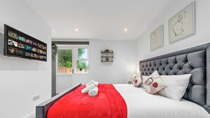 Un dormitorio moderno con una cama grande, un televisor de pantalla plana montado en la pared y una obra de arte sobre la cama.