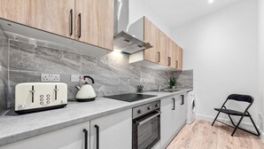 Una cocina moderna con horno empotrado, tostadora y hervidor sobre la encimera.