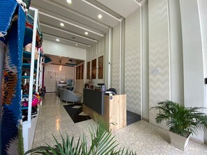 A hotel lobby with a reception desk, seating area, and a staircase leading to the upper floors. - SAMAWA HOTEL (Otavalo)