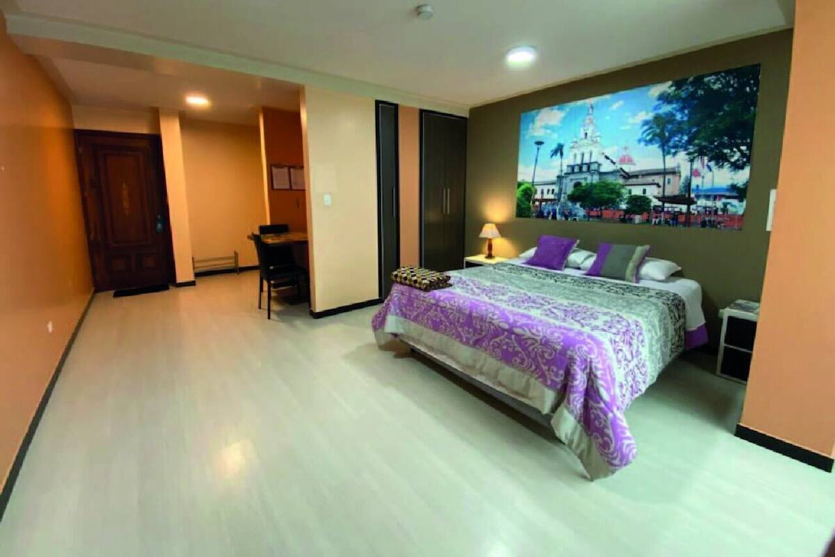 A bedroom with a bed, a desk, and a chair.