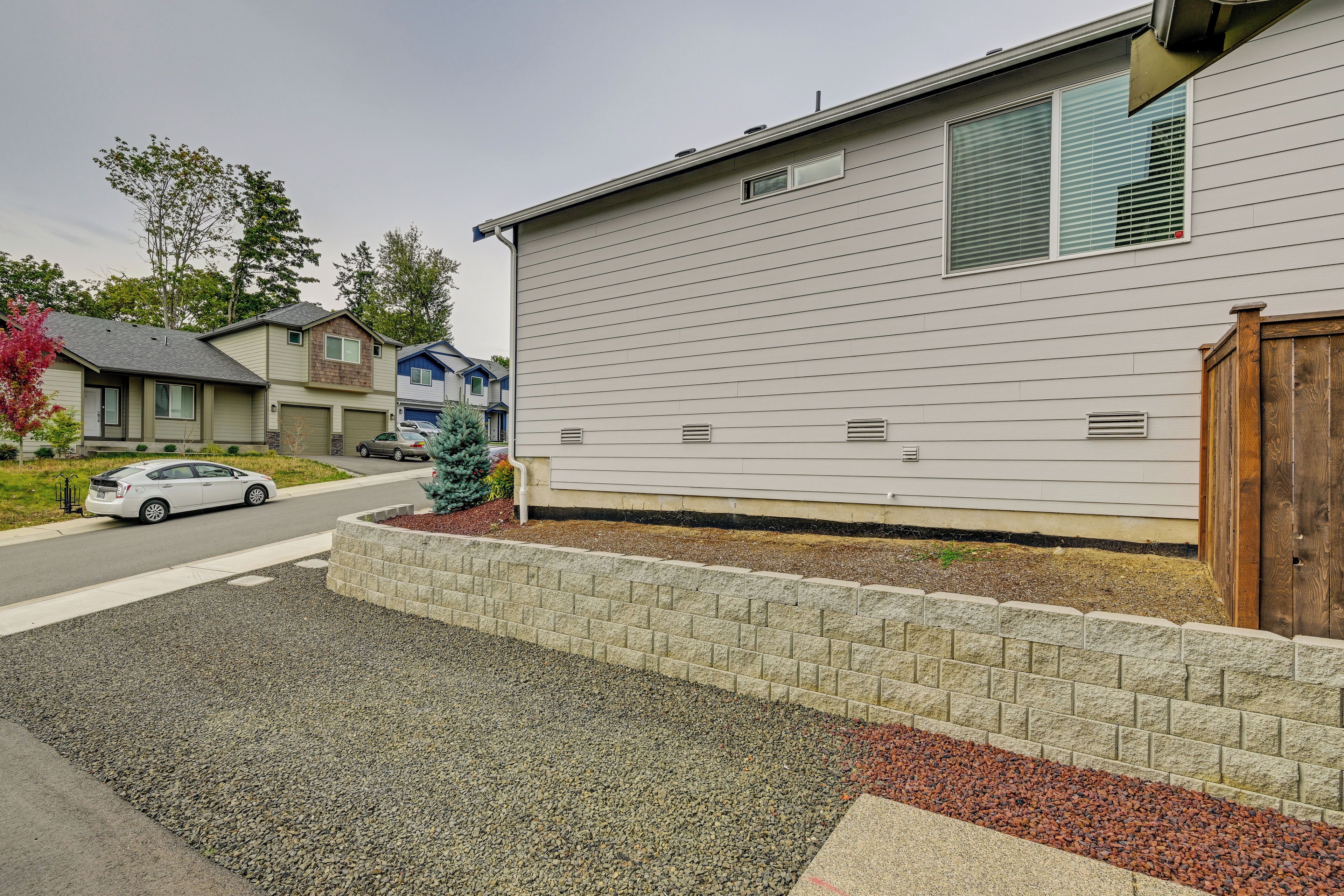 A residential building with a garage, a driveway, and a small garden area with a brick border and gravel.