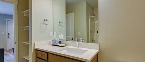A bathroom with a white sink, wooden cabinets, a large mirror, and a toilet.