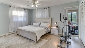 A bedroom with a bed, a nightstand, a ceiling fan, and a window with curtains.