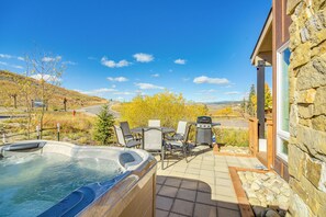 A hot tub, patio furniture, and a stone building with a view of a hilly landscape. - Ski-in/ski-out Granby Townhouse w/ Private Hot Tub (Granby)