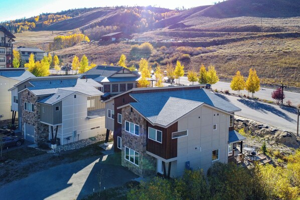 A modern multi-story residential building with a stone facade, large windows, and a flat roof. - Ski-in/ski-out Granby Townhouse w/ Private Hot Tub (Granby)