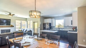 A modern kitchen with a dining area, large windows, and a ceiling fan. - Ski-in/ski-out Granby Townhouse w/ Private Hot Tub (Granby)