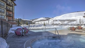 A hot tub area with chairs and a pool, surrounded by buildings and a snowy landscape. - Ski-in/ski-out Granby Townhouse w/ Private Hot Tub (Granby)