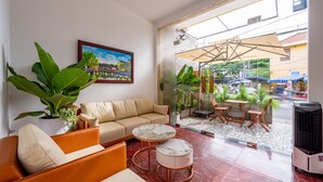 A modern hotel lobby with a sofa, coffee table, and potted plants. - Golden Sun Hotel Hoi An (Da Nang)