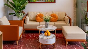 A modern living room with a sofa, two armchairs, a coffee table, and a large plant. - Golden Sun Hotel Hoi An (Da Nang)