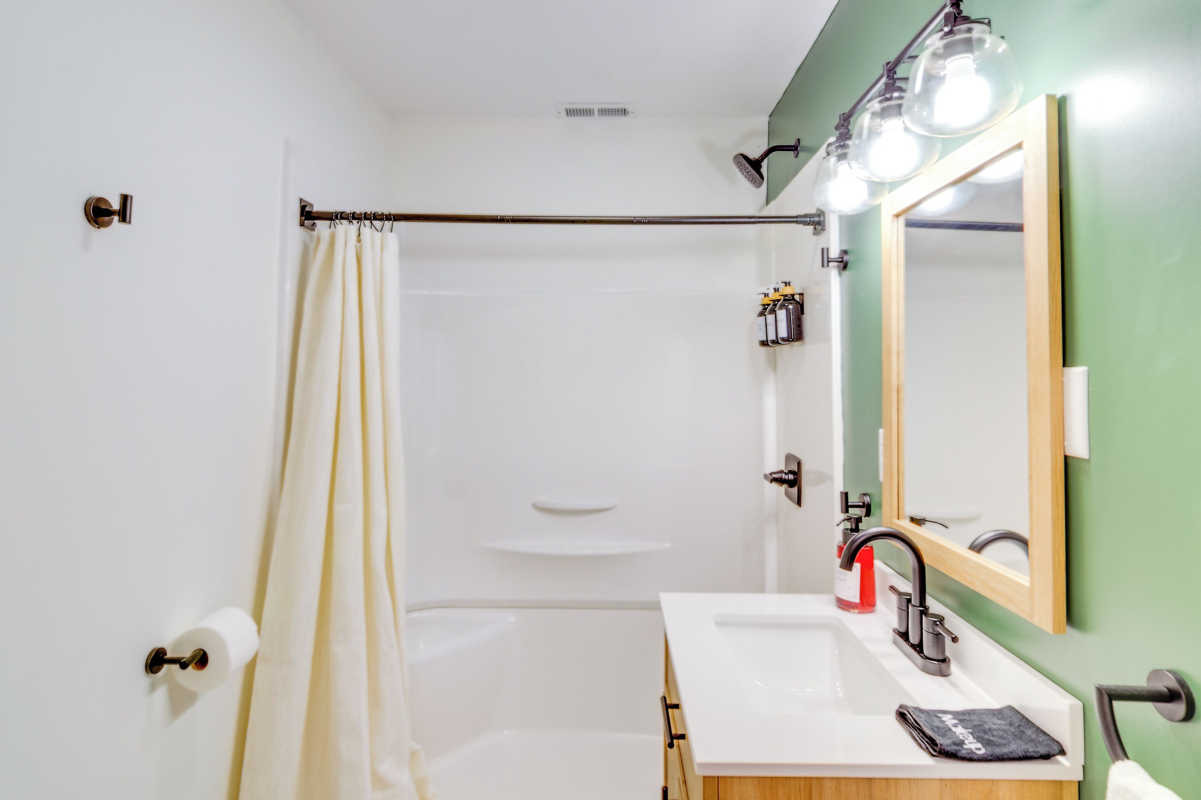Ein modernes Badezimmer mit einem weißen Waschbecken, einem Spiegel und einer Duschvorhang.