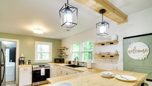 Een moderne keuken met een houten aanrecht, roestvrijstalen apparatuur en een bordje met de tekst 'welcome' aan de muur.
