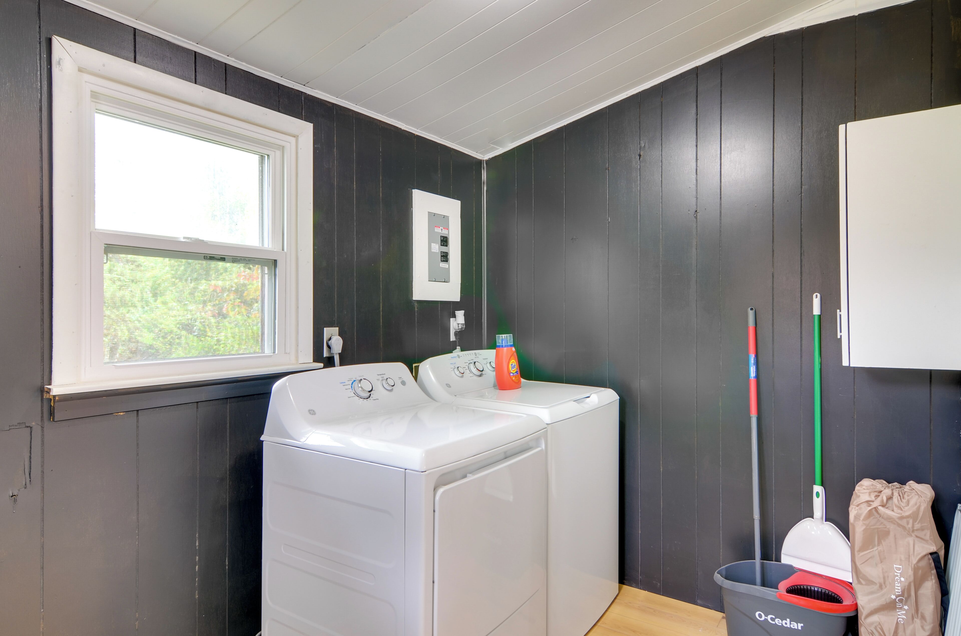 A laundry room with a washing machine, a utility meter, and cleaning supplies.