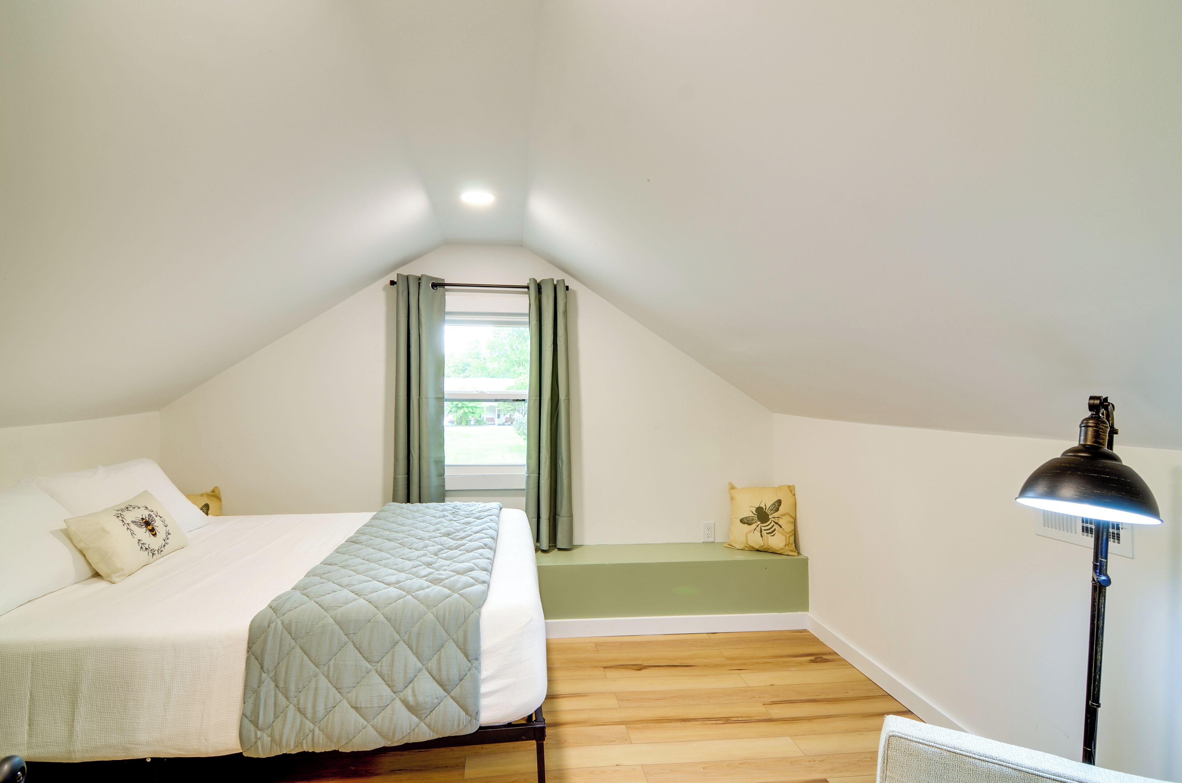 Une chambre à coucher avec un lit, une fenêtre avec des rideaux, une table de chevet et une lampe de sol.