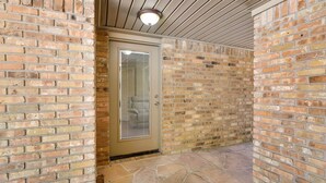 A brick-walled corridor with a door leading to a room.