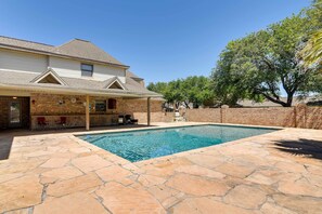 A house with a swimming pool, stone patio, and a covered outdoor seating area.
