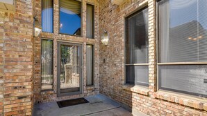 A corner of a building with a brick facade, large windows with blinds, and a small entrance area with a doormat. - Expansive Home w/ Pool Table ~ 15 Mi to Galveston! (Texas City)