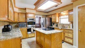 A kitchen with wooden cabinets, granite countertops, stainless steel appliances, and a skylight. - Expansive Home w/ Pool Table ~ 15 Mi to Galveston! (Texas City)