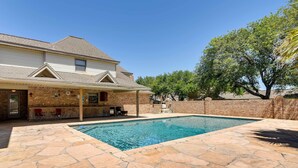 A house with a swimming pool, stone patio, and a covered outdoor seating area. - Expansive Home w/ Pool Table ~ 15 Mi to Galveston! (Texas City)
