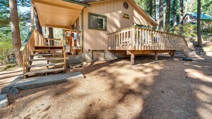A cabin with a covered porch, a deck, and a small staircase leading to the entrance.
