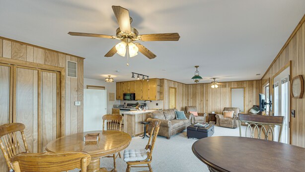A spacious living area with a wooden interior, a dining table, and a kitchen area with wooden cabinets. - Scenic Views & Yard: Mississippi River Retreat! (Albany)