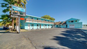 A motel with a two-story structure, a parking lot, and a signboard.