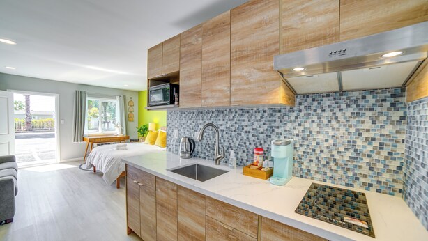 A modern kitchen with wooden cabinets, a stainless steel sink, and a tiled backsplash.